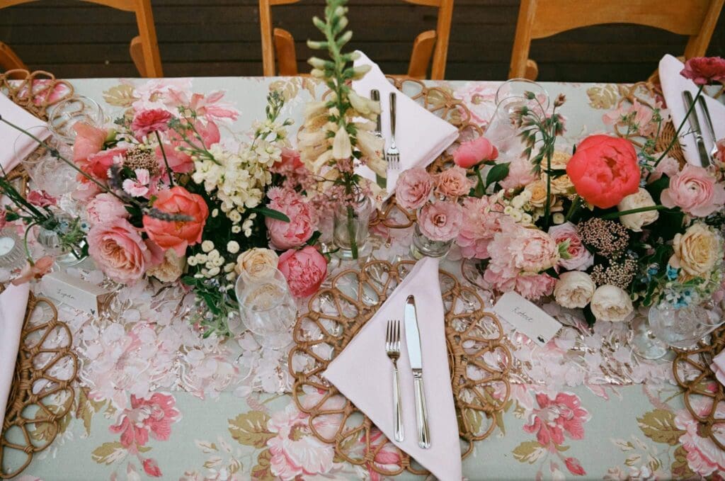 Garden-inspired reception table with coral florals and illustrated menus at a small backyard wedding