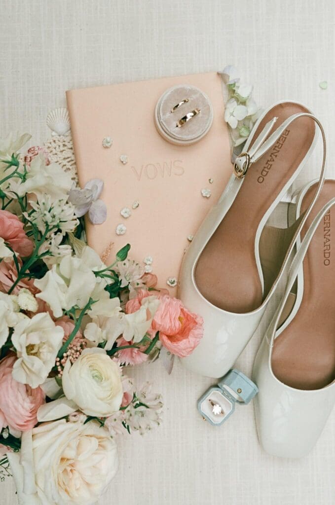 Flat lay of wedding bouquet, blush shoes, and custom invitation suite