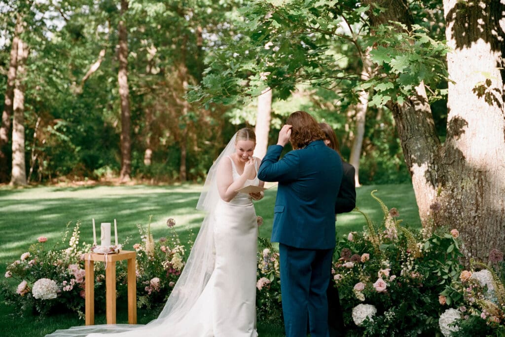 Bride wiping her eyes as she reads her vows during her wedding on Cape Cod