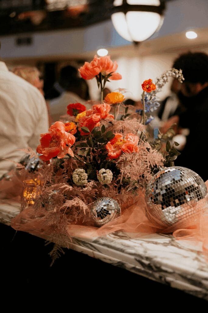 Grounded floral arch installation with vibrant, movement-filled blooms in bold pink, coral, and peach hues