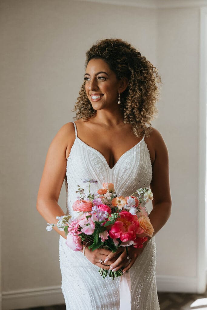 Bride holding a vibrant bouquet of pinks and corals with garden-style movement