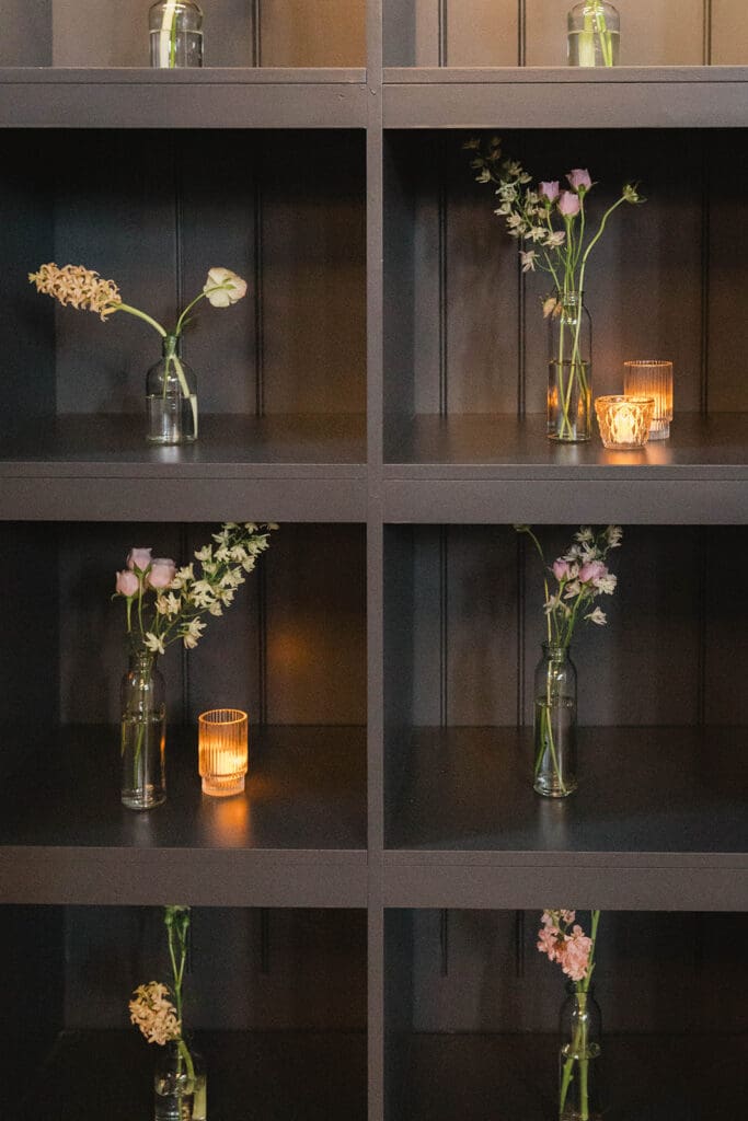 Statement floral arrangement in front of black shelving during cocktail hour, creating a design bridge between rooms