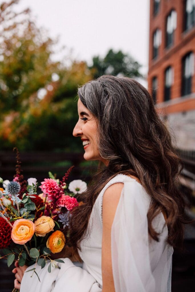 Bride holding rich, seasonal flowers with texture and movement in warm fall tones