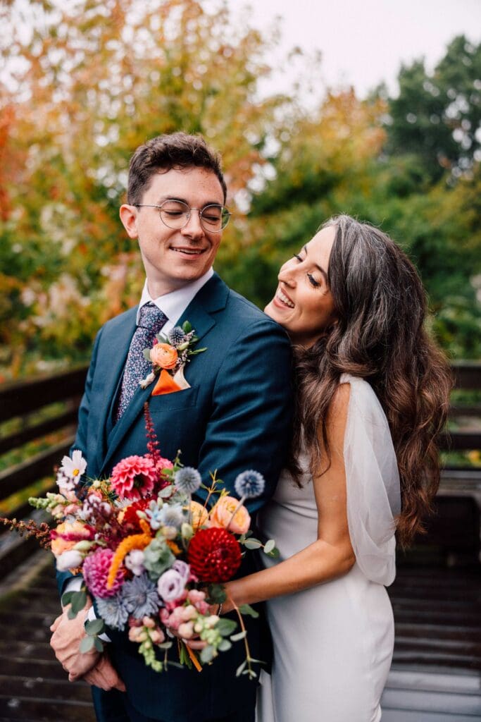 Newlyweds embracing with wildly colorful autumn floral bouquets