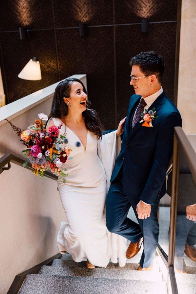 Bride in a white dress laughing while holding a textured fall wedding bouquet