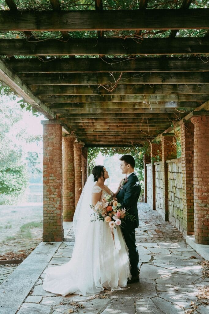 Newlyweds under wooden arbor at Turner Hill wedding
