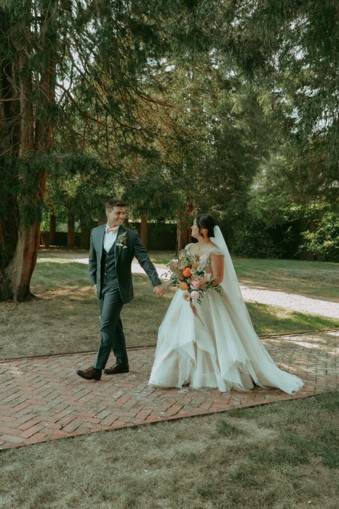 Bride and groom walking hand in hand across the lawn after a ceremony