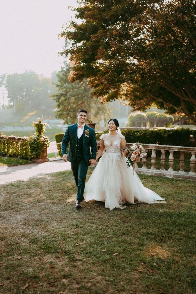 Bride and groom at their outdoor ceremony with floral pillars designed to repurpose wedding flowers later in the day