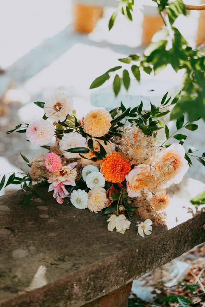 Wedding flowers in blush and apricot tones laying on a stone bench