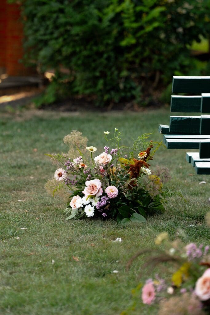 Repurposed wedding bouquet and ceremony blooms artfully arranged at the end of the aisles