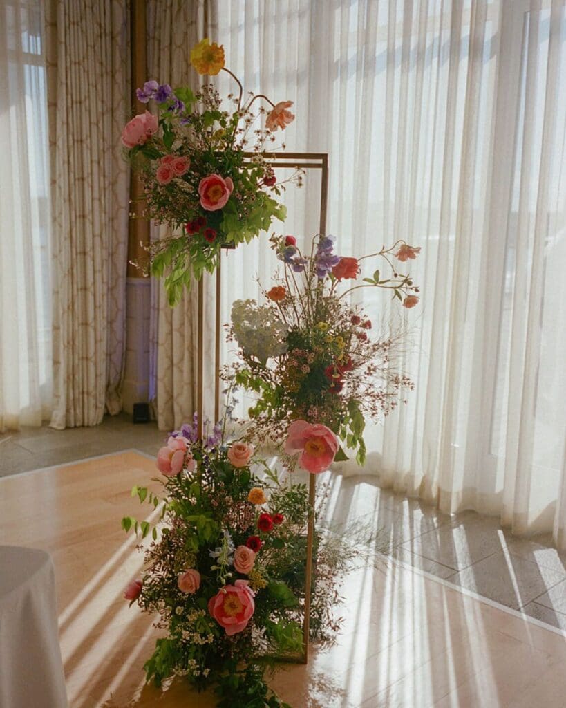 Colorful wedding flowers arranged on a modern gold frame, bringing seasonal May wedding blooms into the Beauport Hotel Gloucester reception space.