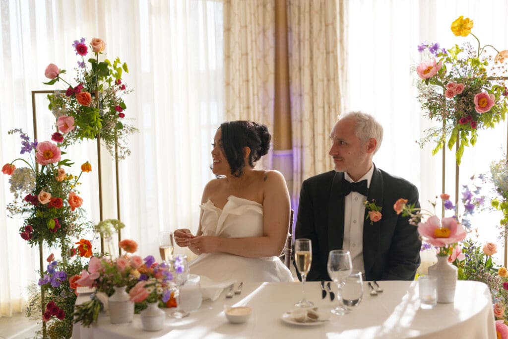 Sweetheart table at a Beauport Hotel Gloucester wedding, surrounded by colorful seasonal flowers that bring the beach wedding vibe indoors.