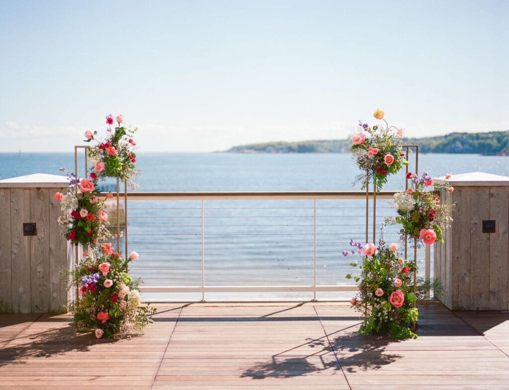Oceanfront ceremony setup at the Beauport Hotel in Gloucester, with colorful wedding flowers framing the view for a beachside wedding.