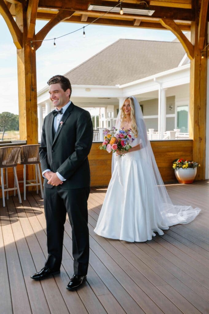 Bride approaches groom for their first look at New Seabury Country Club, holding a modern wedding bouquet filled with bright, seasonal blooms.