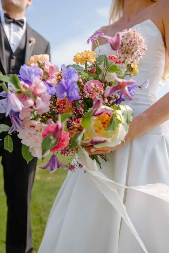 Bright, colorful bouquet featuring peonies, clematis, garden roses, and sweet peas designed by Cape Cod wedding florist Rumphius Farms.