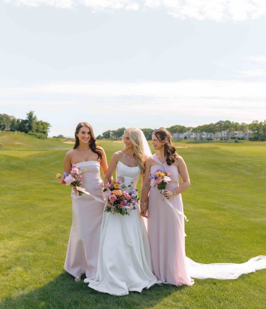 Bride and bridesmaids in soft blush gowns holding colorful modern bouquets at New Seabury Country Club.