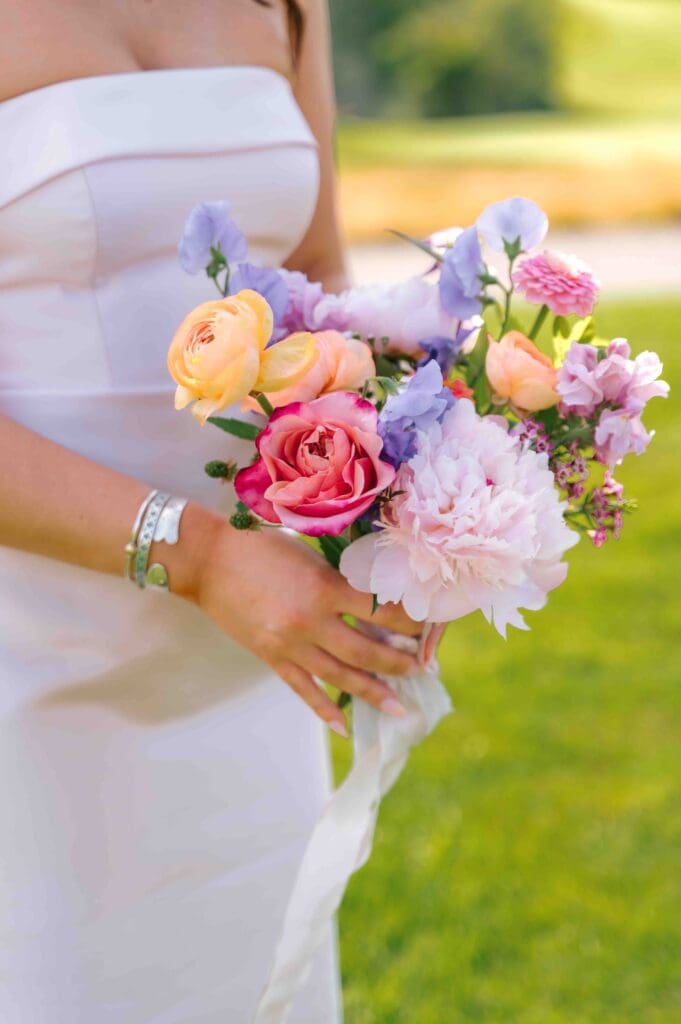 Bright garden-style bouquet with pink roses, peach ranunculus, and lavender sweet peas, perfect for a modern Cape Cod wedding.